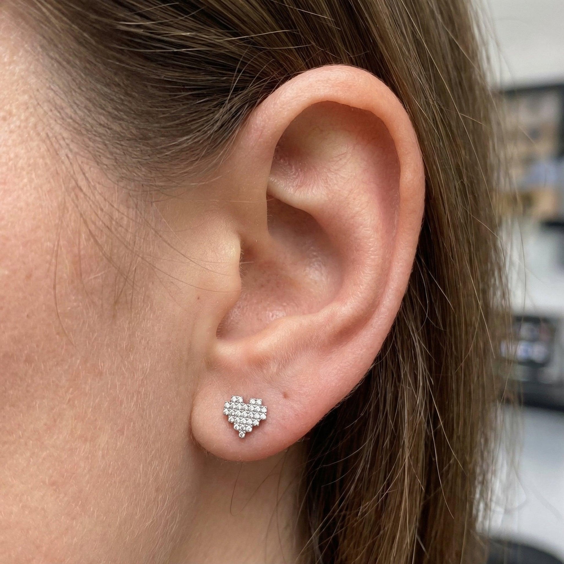 Silver paved heart stud worn securely in a standard lower piercing.