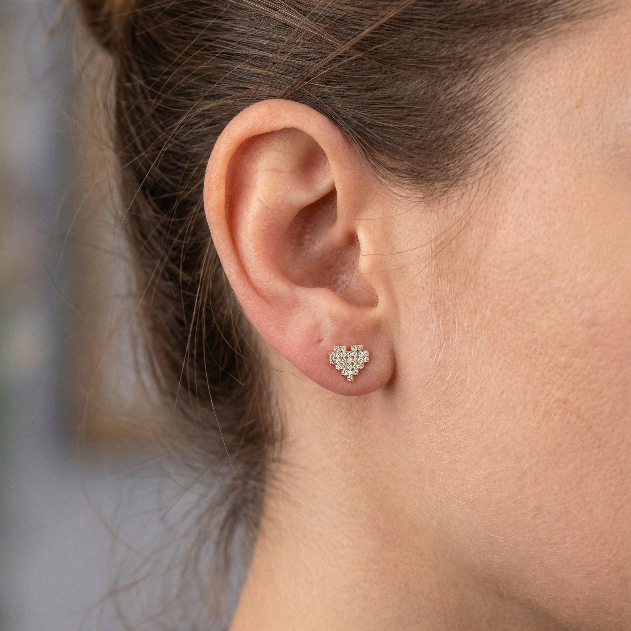 Gold paved heart cartilage earring styled cleanly in a standard lower placement.