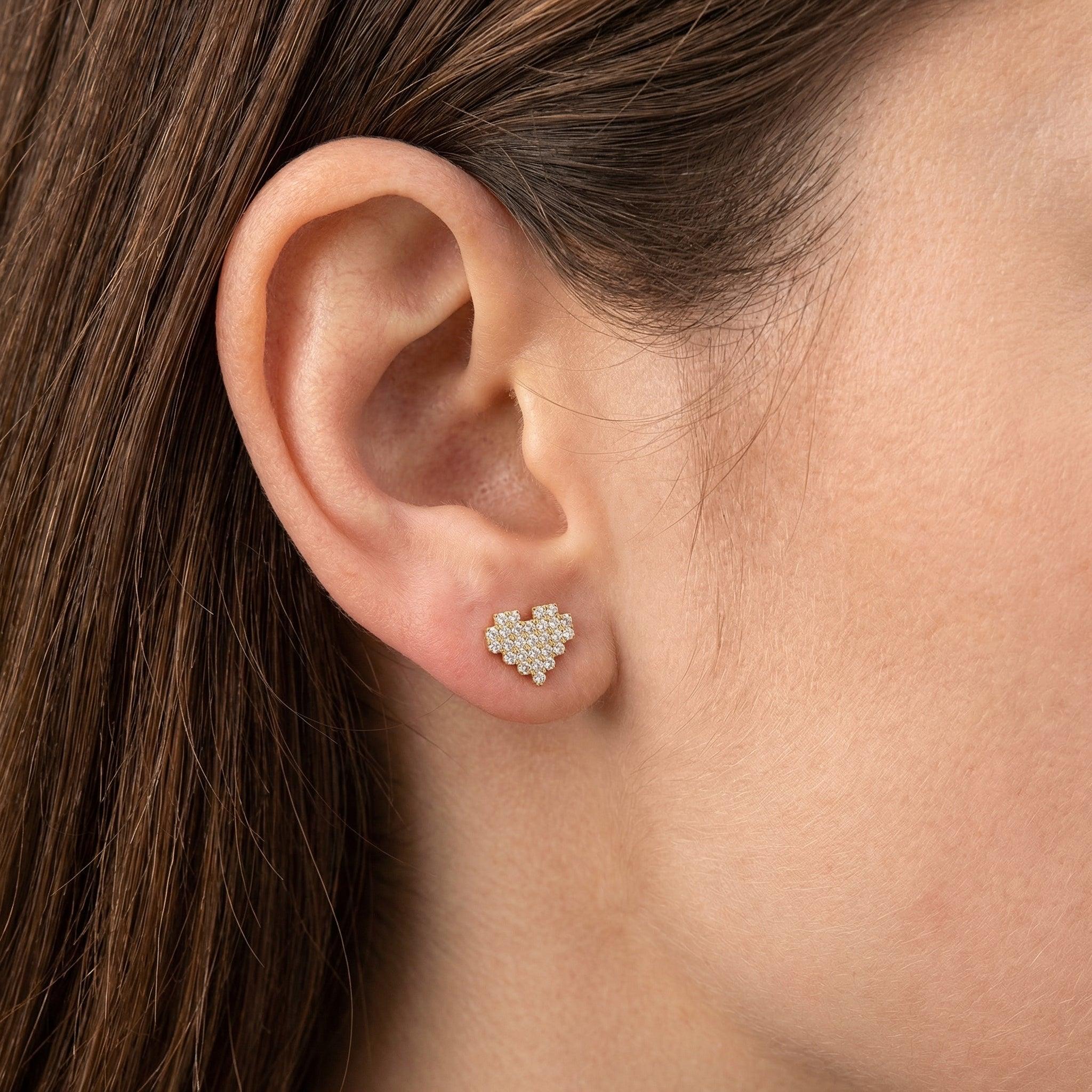 Gold paved heart cartilage earring styled cleanly in a standard lower placement.