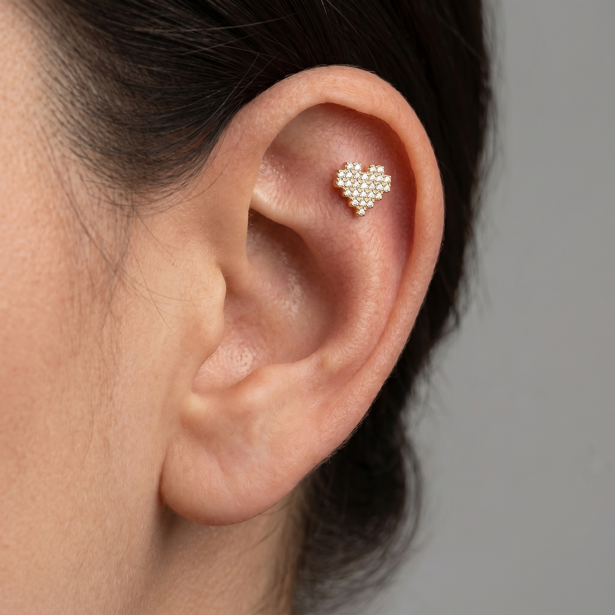 Gold paved heart stud worn cleanly in an upper cartilage piercing.