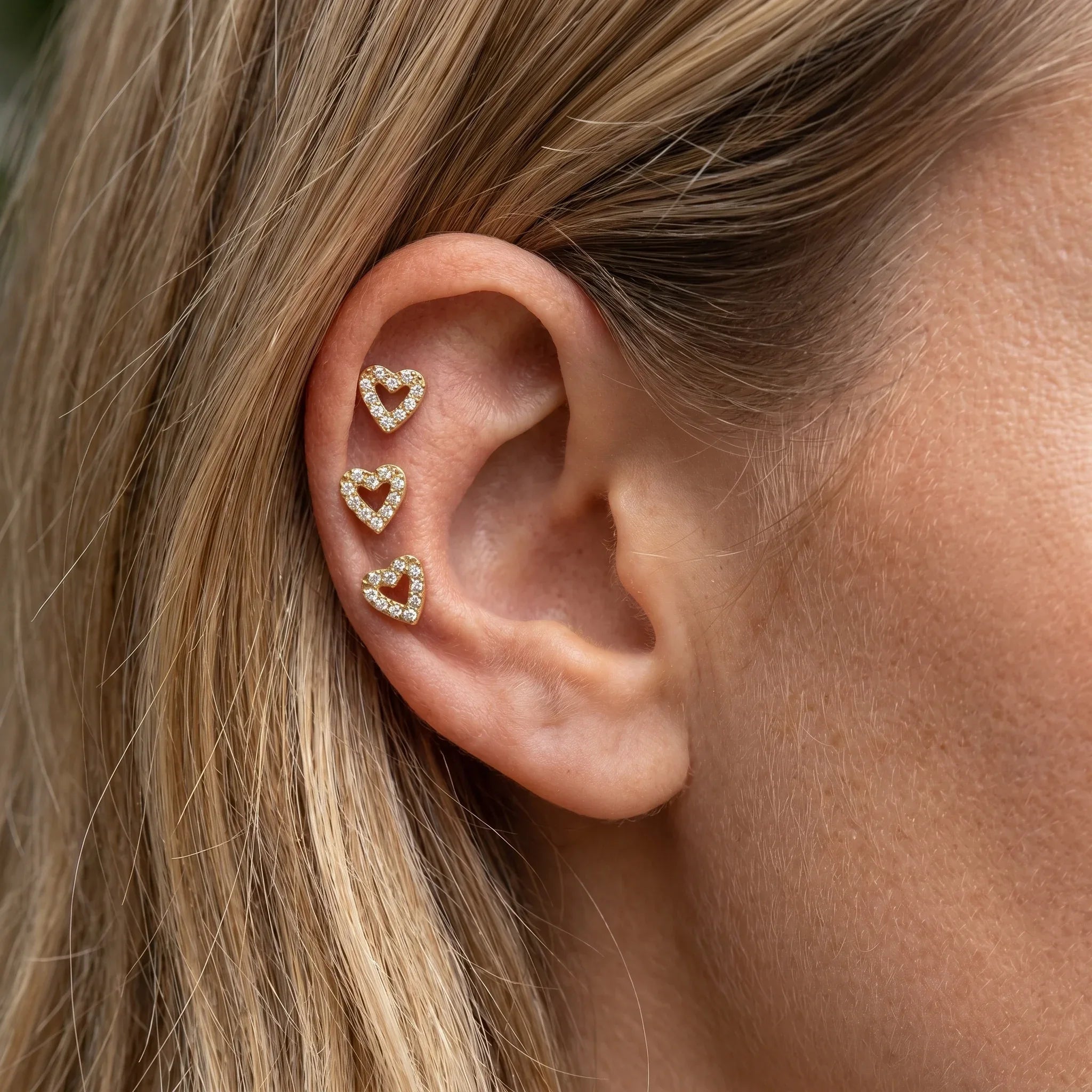 Three gold romantic cartilage labrets styled in multiple piercings.