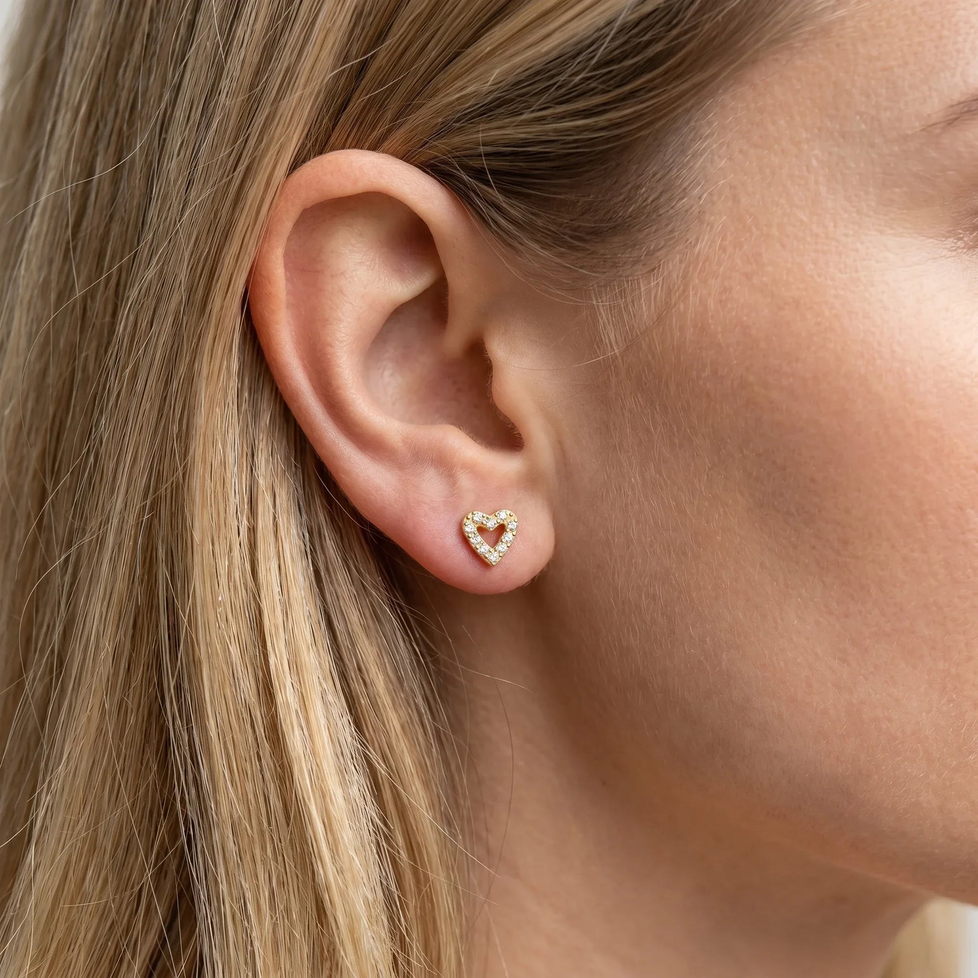 Gold romantic cartilage worn in a standard piercing.
