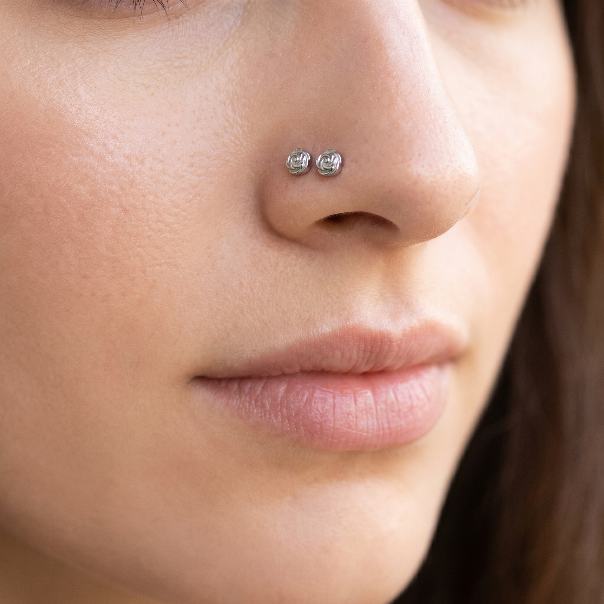 Two rose nose studs styled as a double nose piercing on one nostril