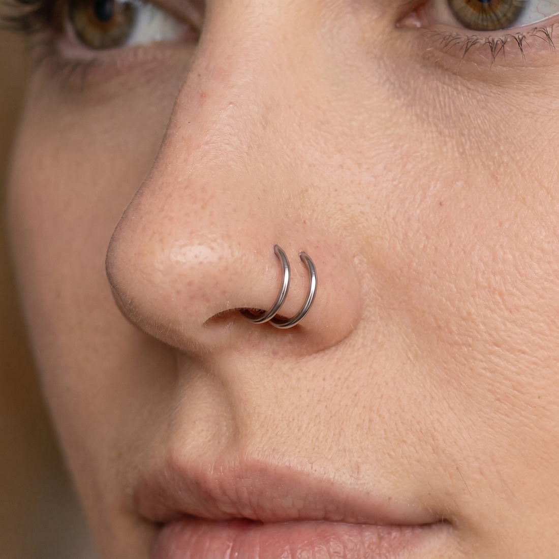Two seamless nose hoops styled as a double nose piercing on one nostril