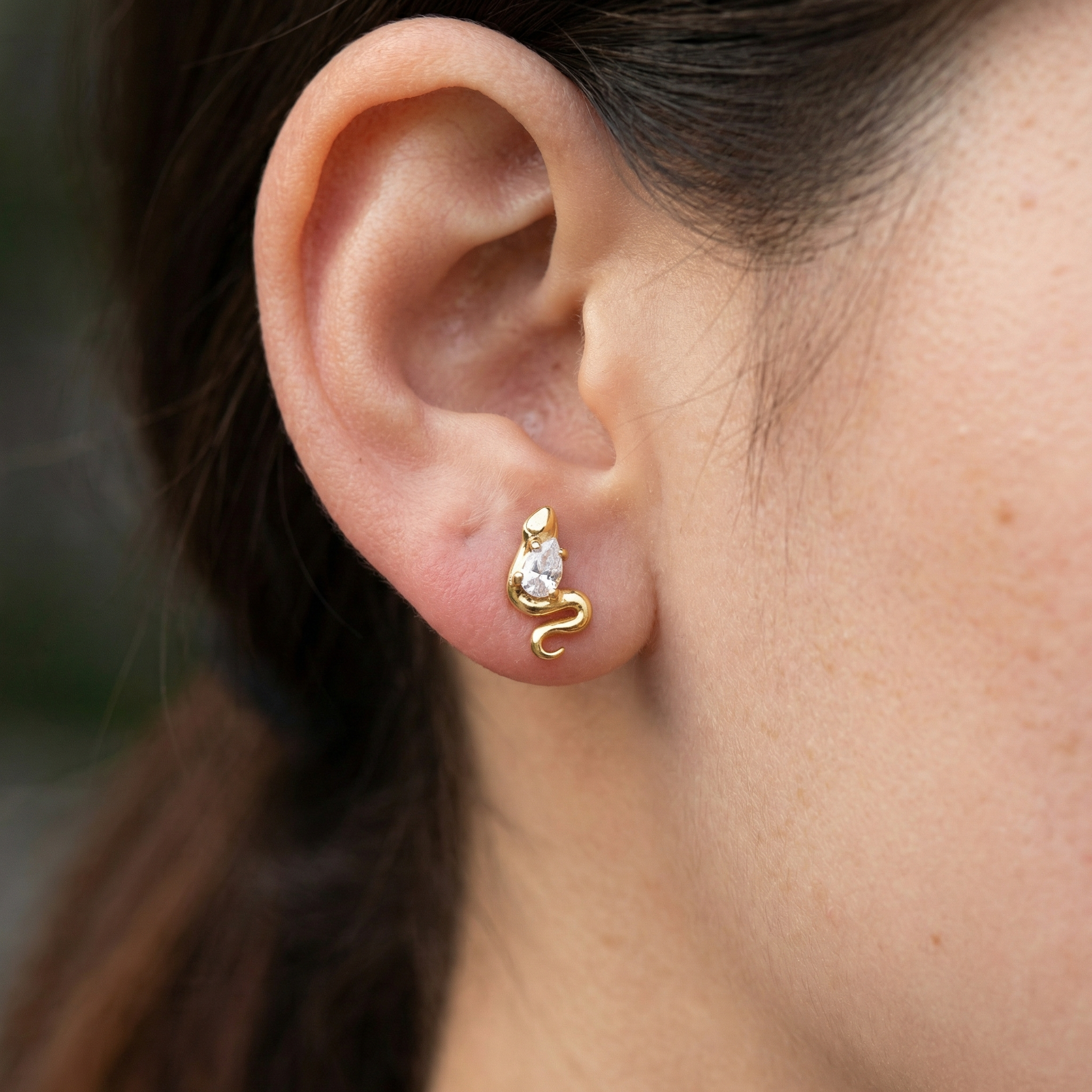 Gold snake zircon jewelry piece styled cleanly in a standard lower piercing