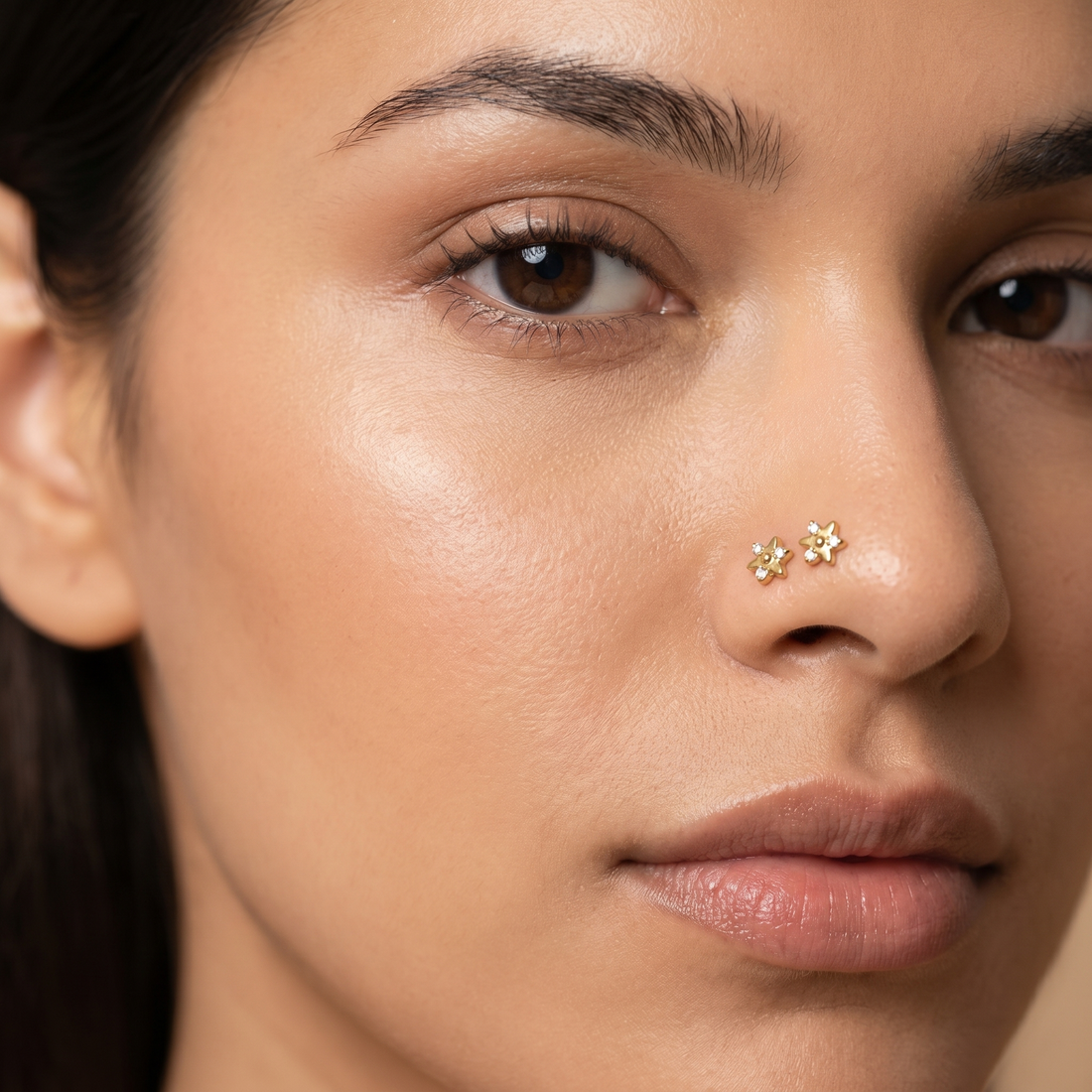 Two star nose studs styled as a double nose piercing on one nostril