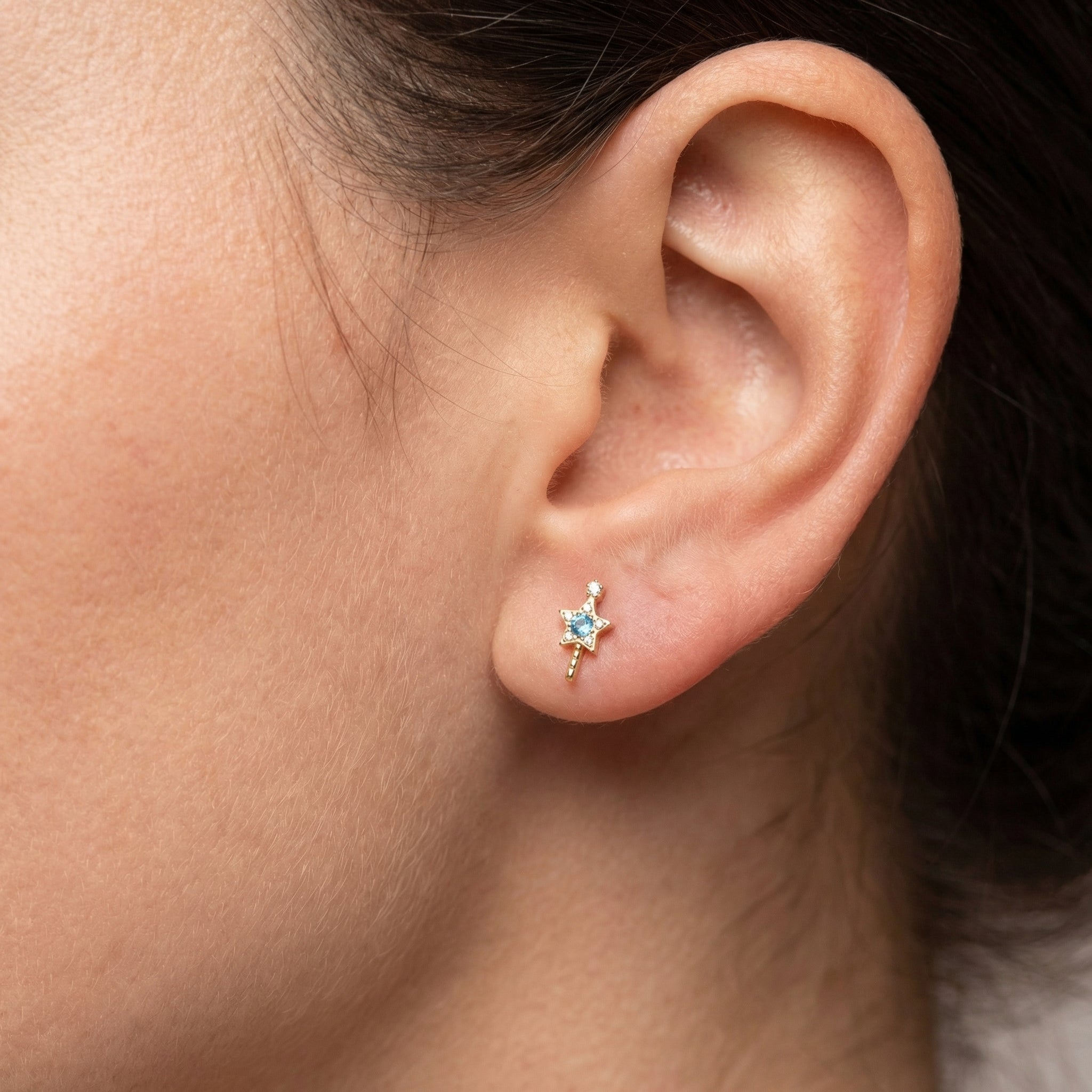 Gold star wand resting cleanly within a standard lower earring configuration.