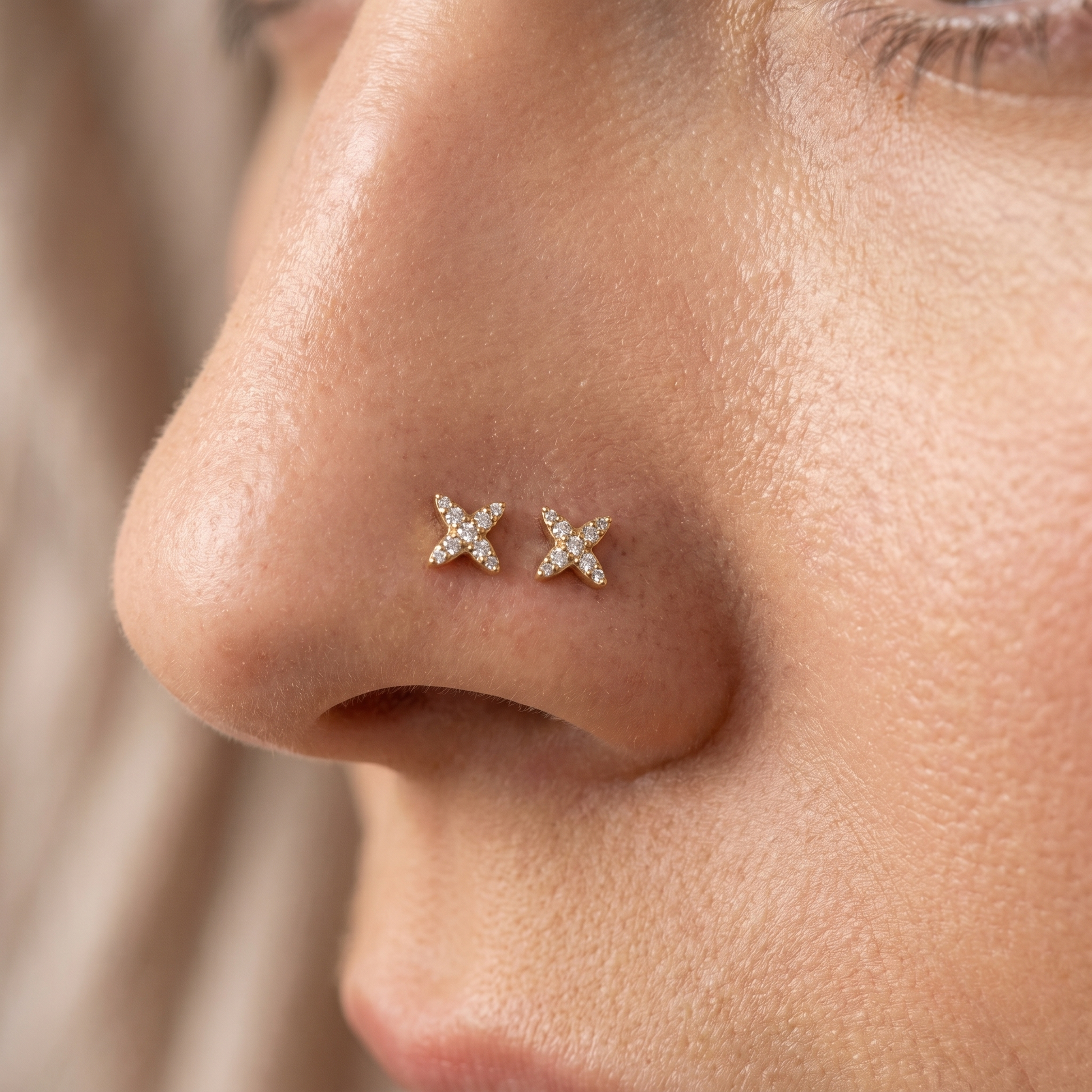 Two starburst nose studs styled as a double nose piercing on one nostril