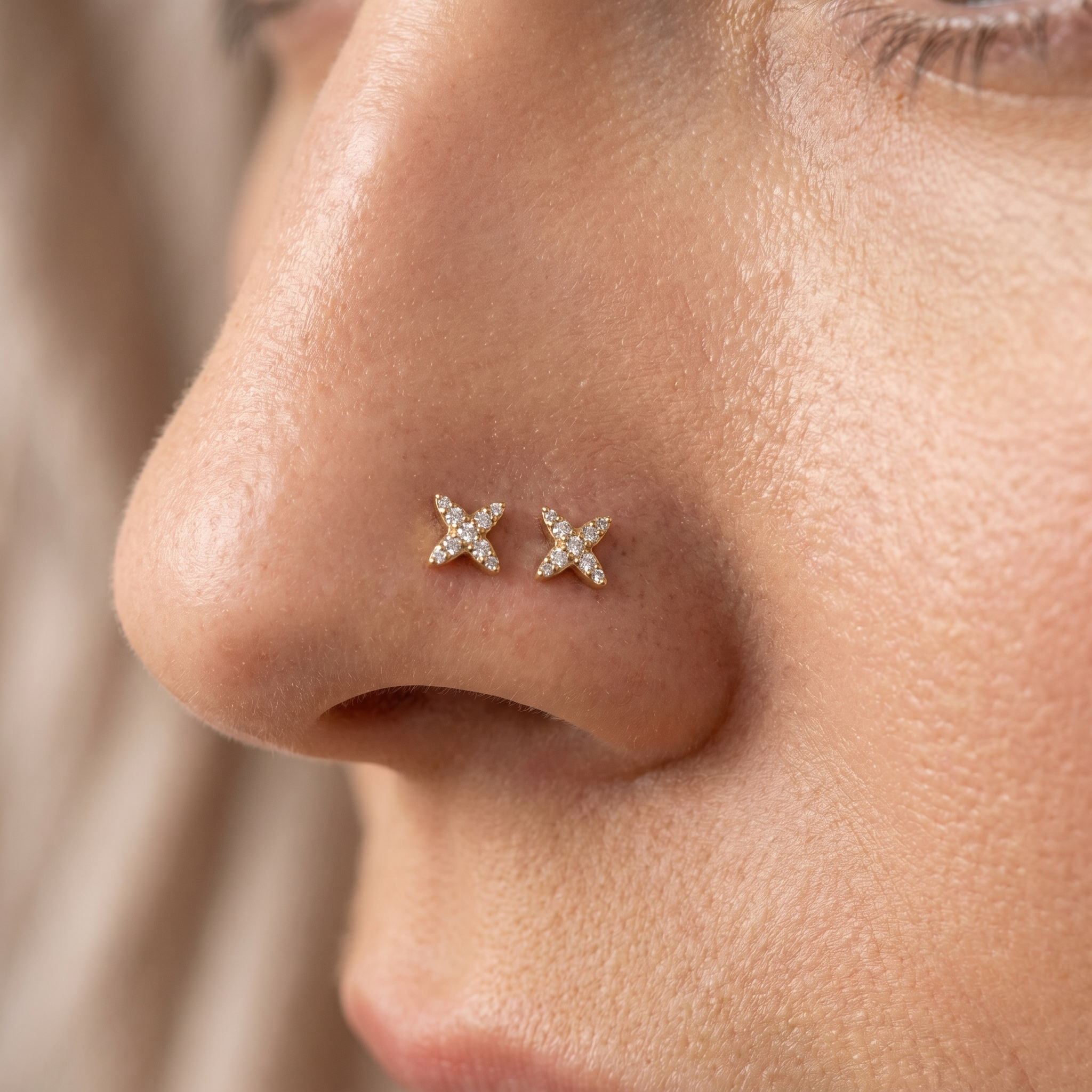 Two starburst nose studs styled as a double nose piercing on one nostril