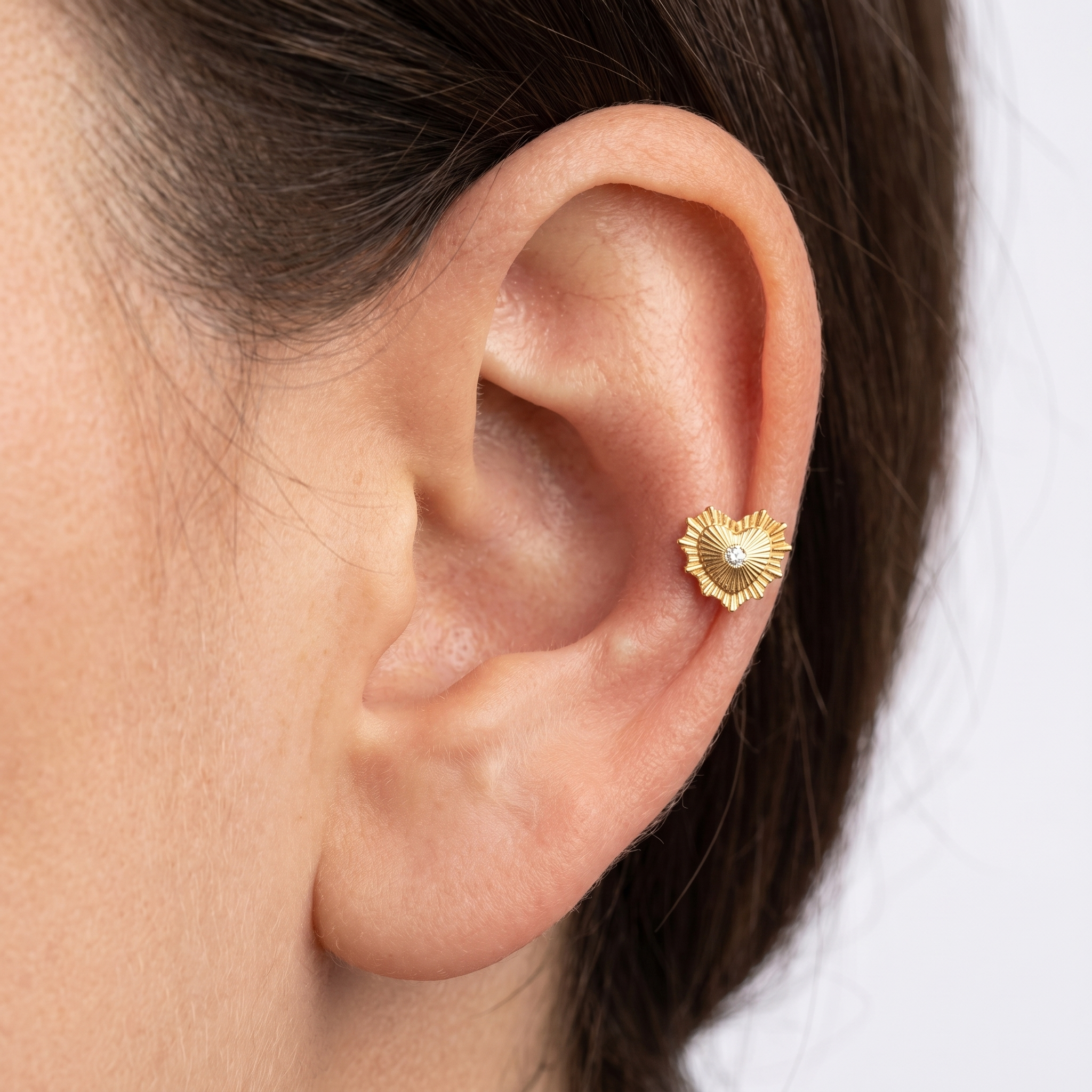 Model showcasing a gold sunburst heart cartilage earring styled in a mid-