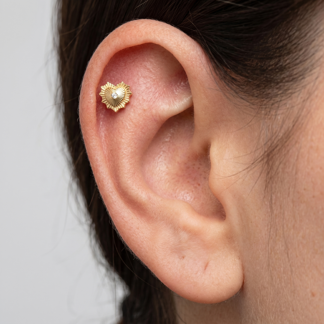 Gold sunburst heart zircon stud — flat helix piercing placement