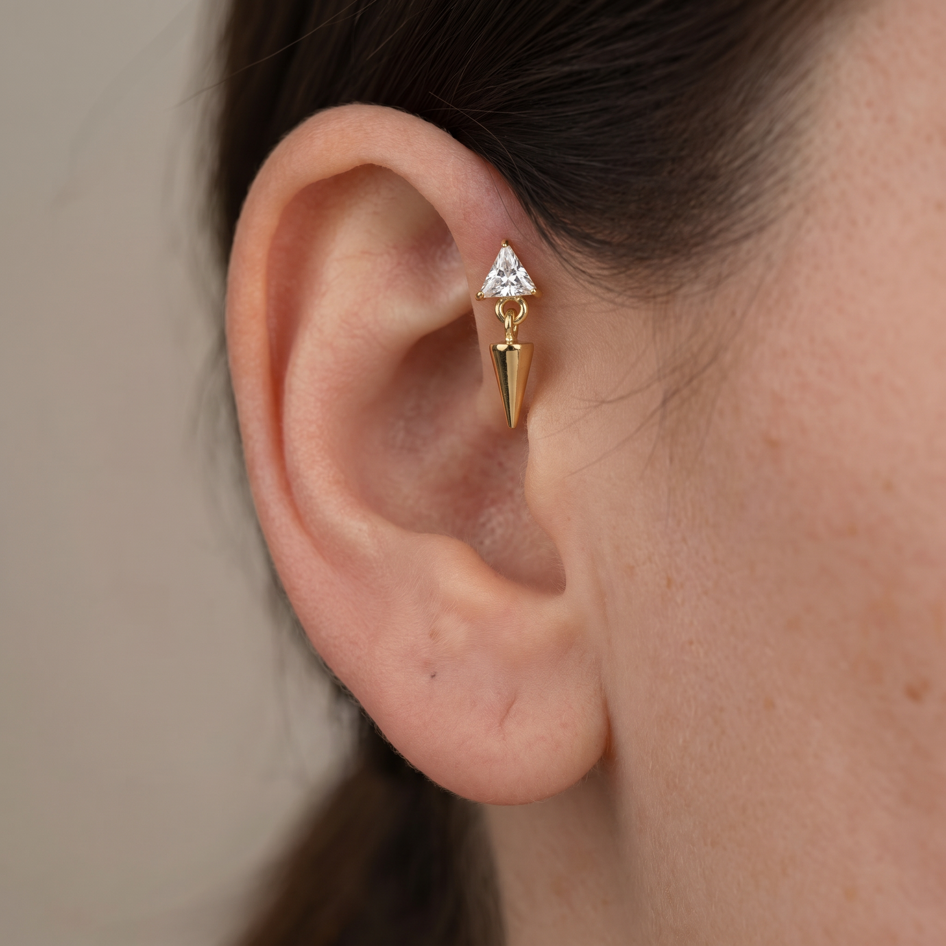 Gold triangle zircon spike dangle jewelry worn securely in a model's cartilage