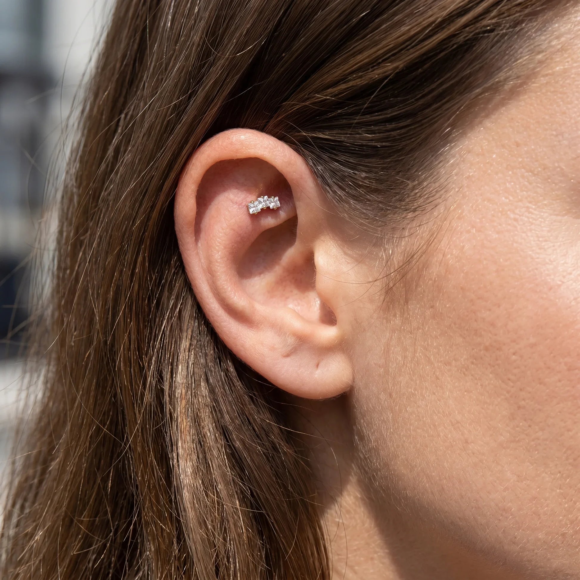 Gold triple zircon faux stud worn beautifully in a female ear.