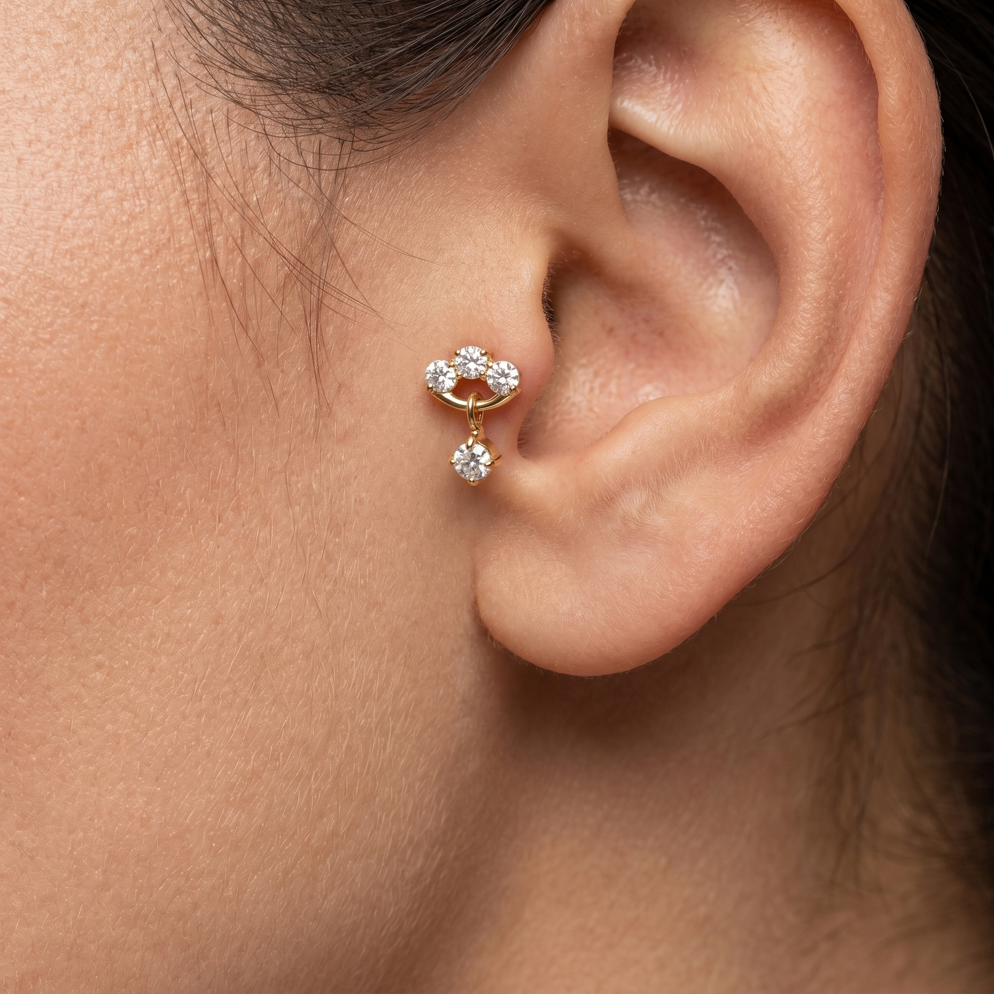 Close-up profile of a gold triple zircon dangle stud worn securely in