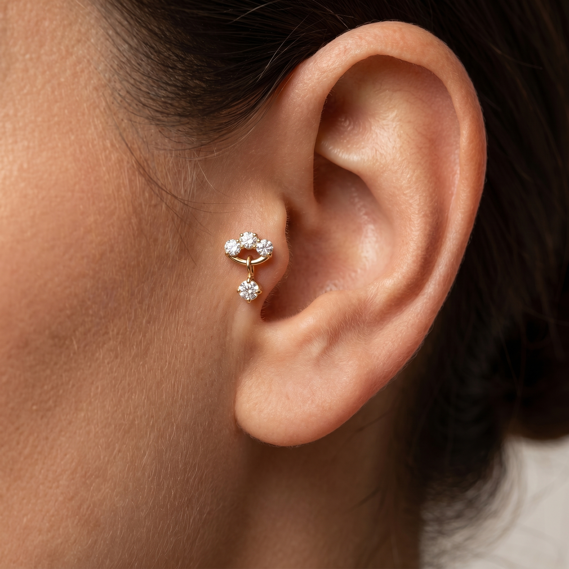 Model showcasing a gold triple zircon dangle cartilage earring styled neatly within