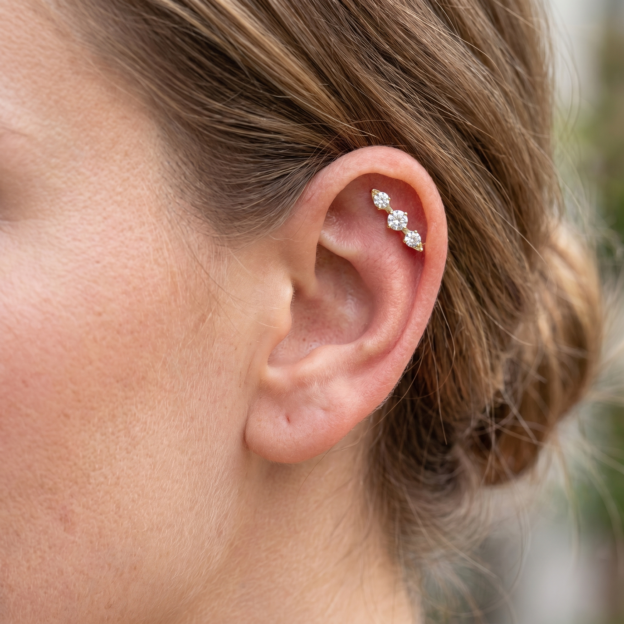 Gold triple zircon cluster cartilage earring styled beautifully within the upper cartilage
