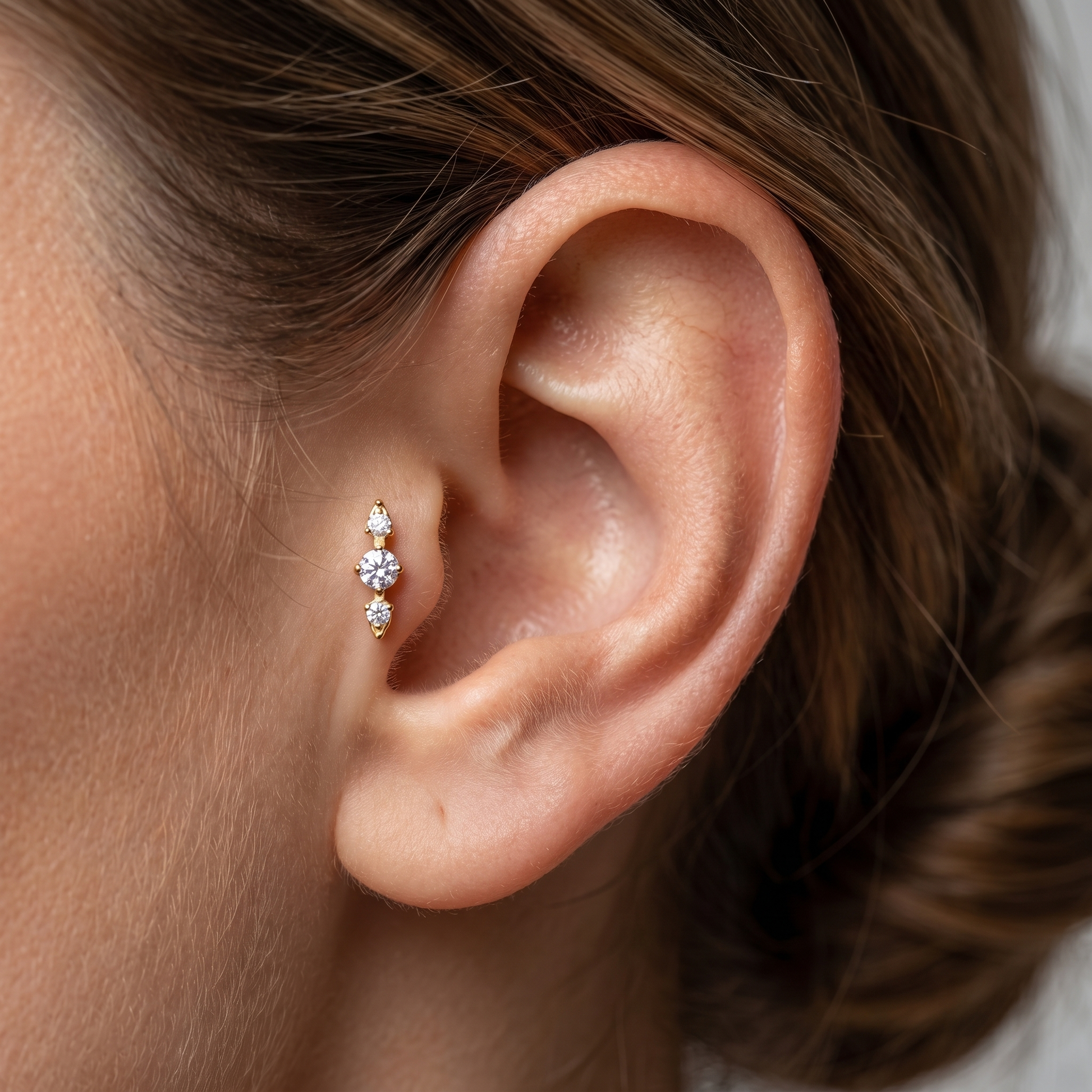 Close-up profile of a gold triple zircon cluster stud worn securely in