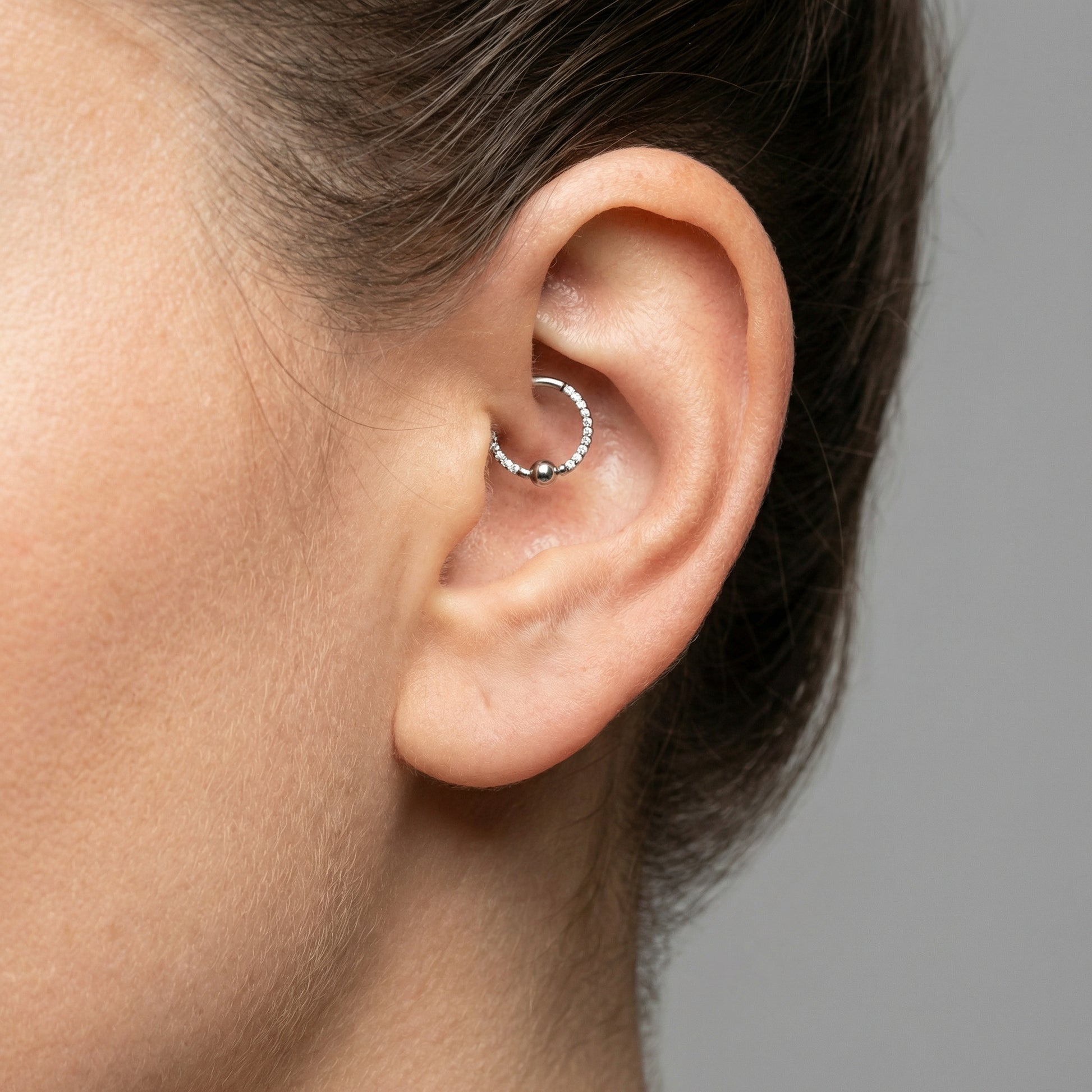 Silver zircon center bead clicker ring styled elegantly in a model's piercing.