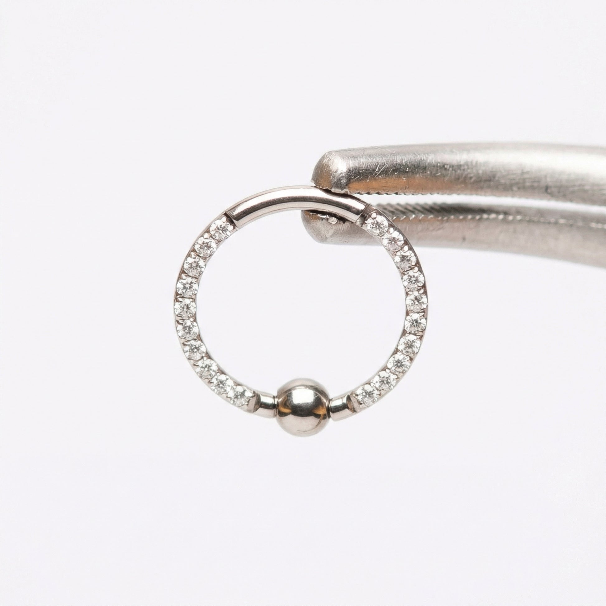 Earrings For A Daith Piercing - Piercing pliers gripping a