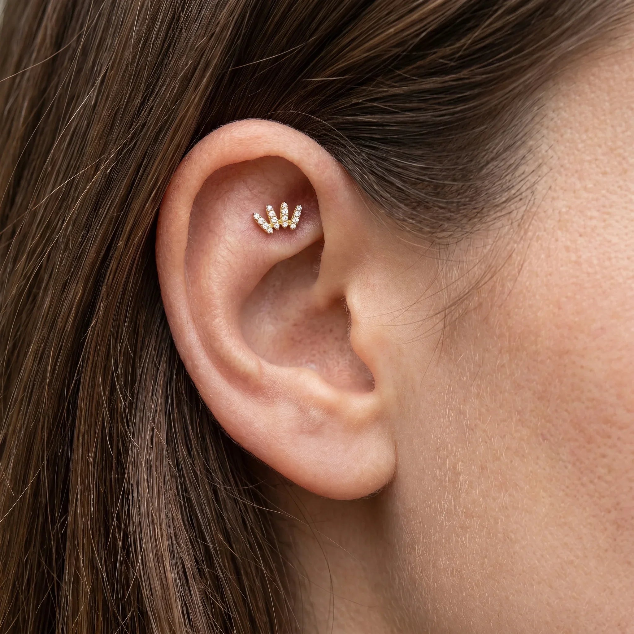 Gold faux crawler worn in a cartilage ear piercing.