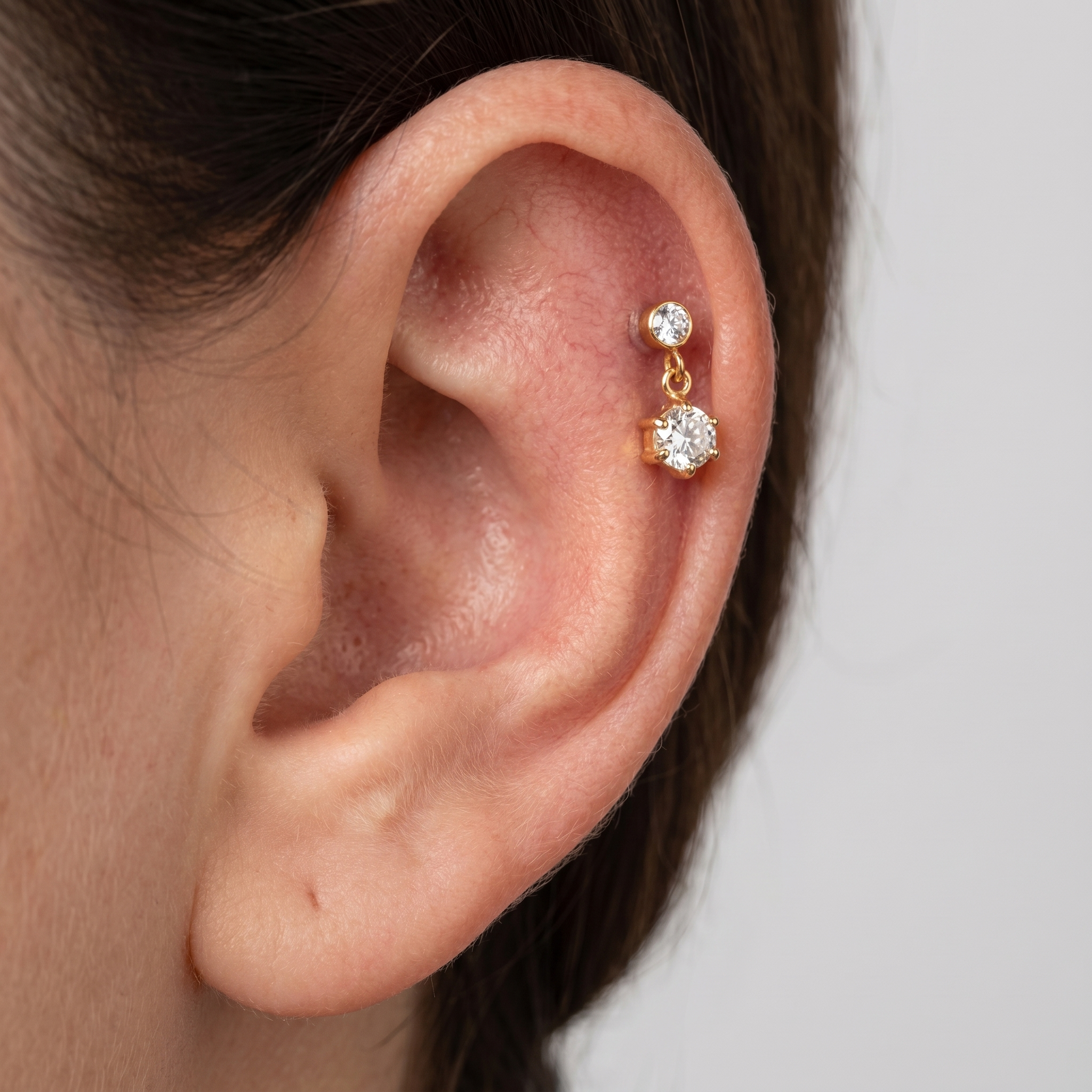 Gold zircon dangle piercing jewelry styled securely in the upper flat cartilage