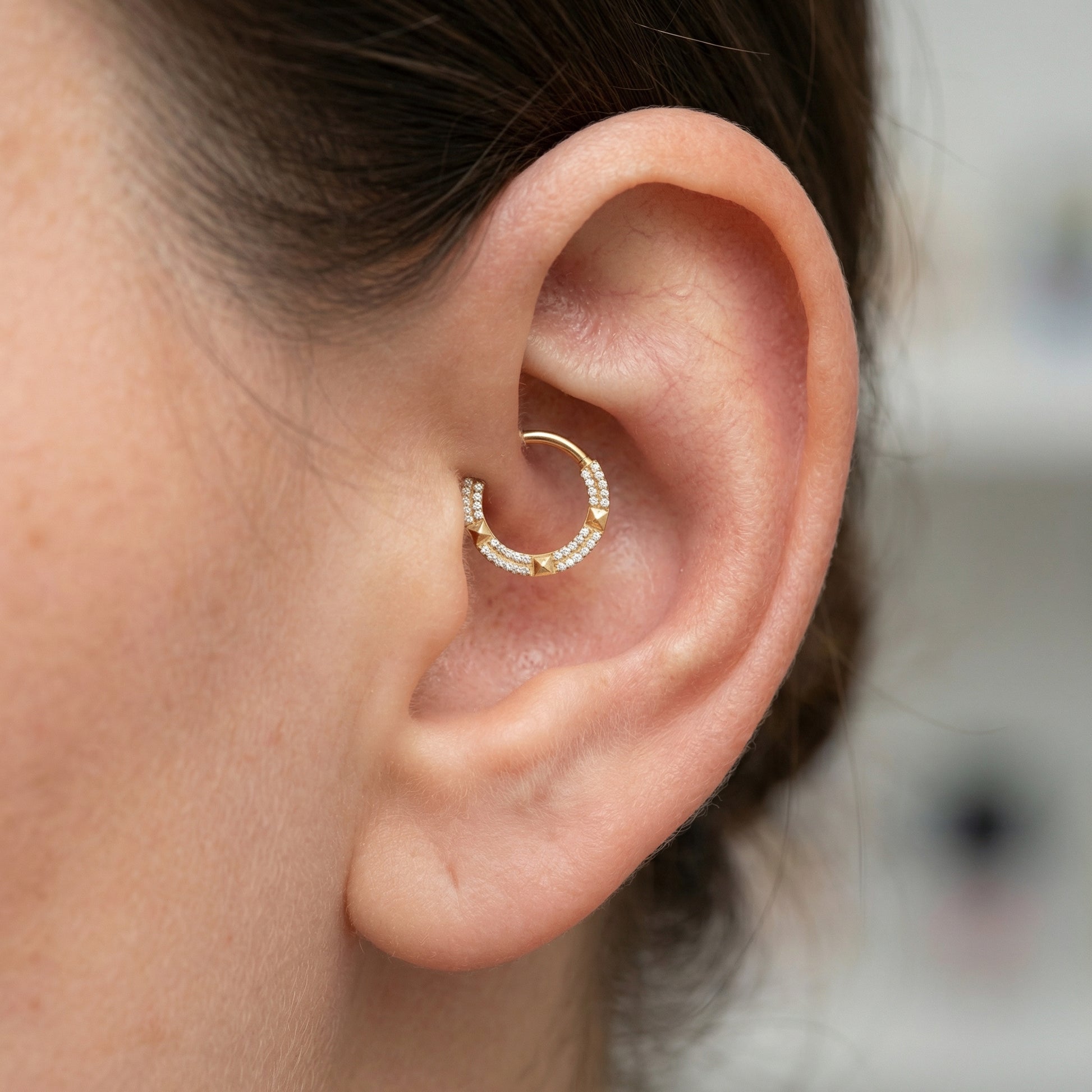 Gold geometric zircon hinged clicker hoop styled beautifully inside a model's inner