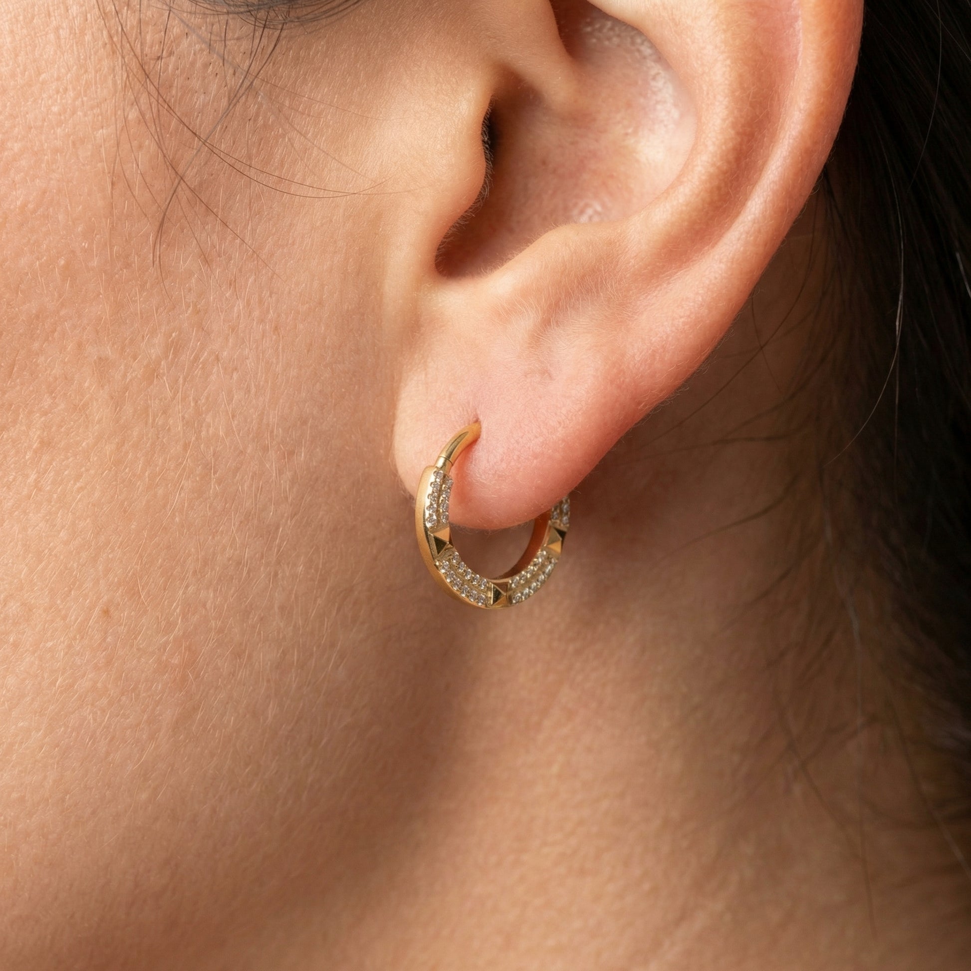 Model showcasing a gold geometric zircon clicker perfectly placed in her standard