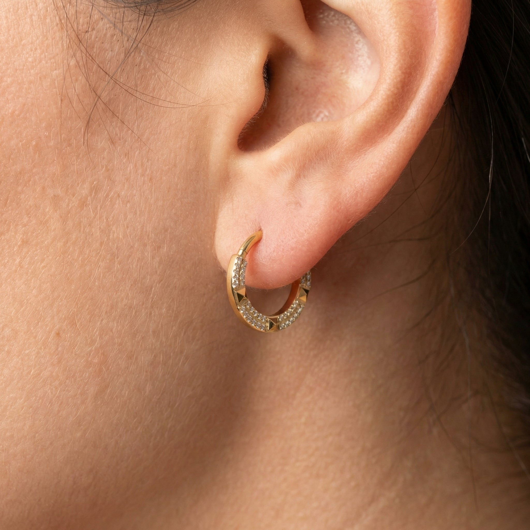 Model showcasing a gold geometric zircon clicker perfectly placed in her standard