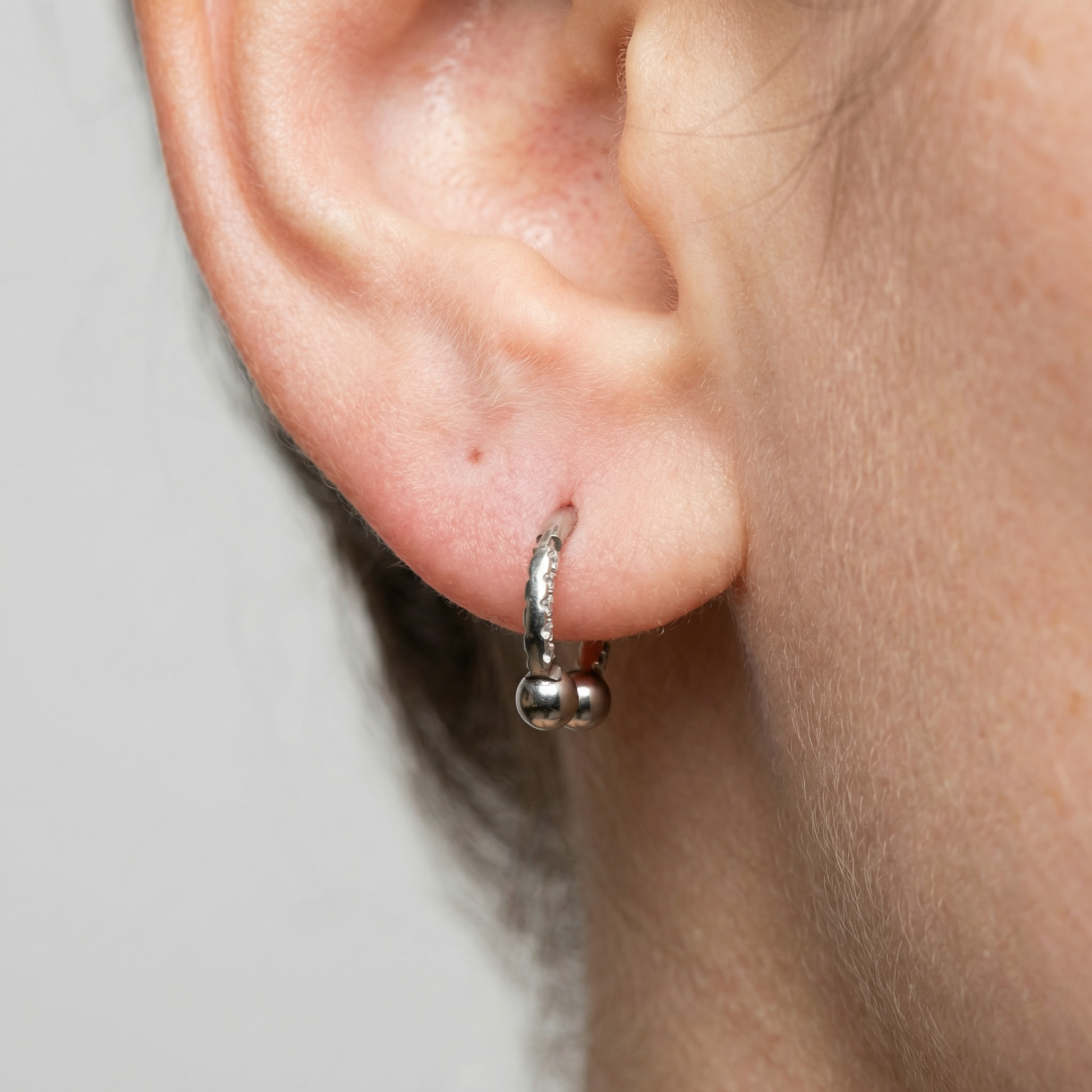 Silver zircon pave hinged horseshoe clicker hoop worn in a standard lower