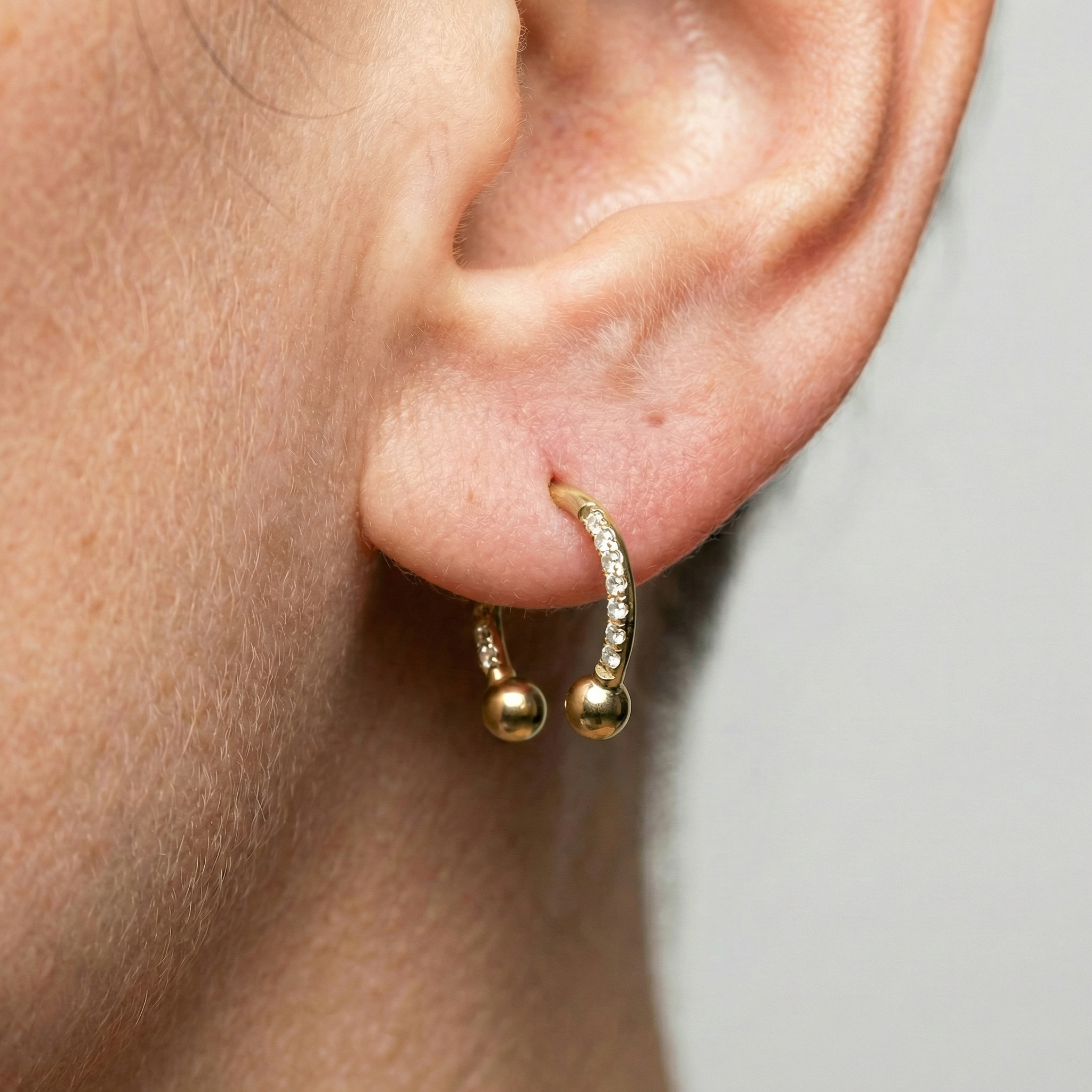 Model displaying a gold zircon pave hinged horseshoe clicker hoop perfectly fitted