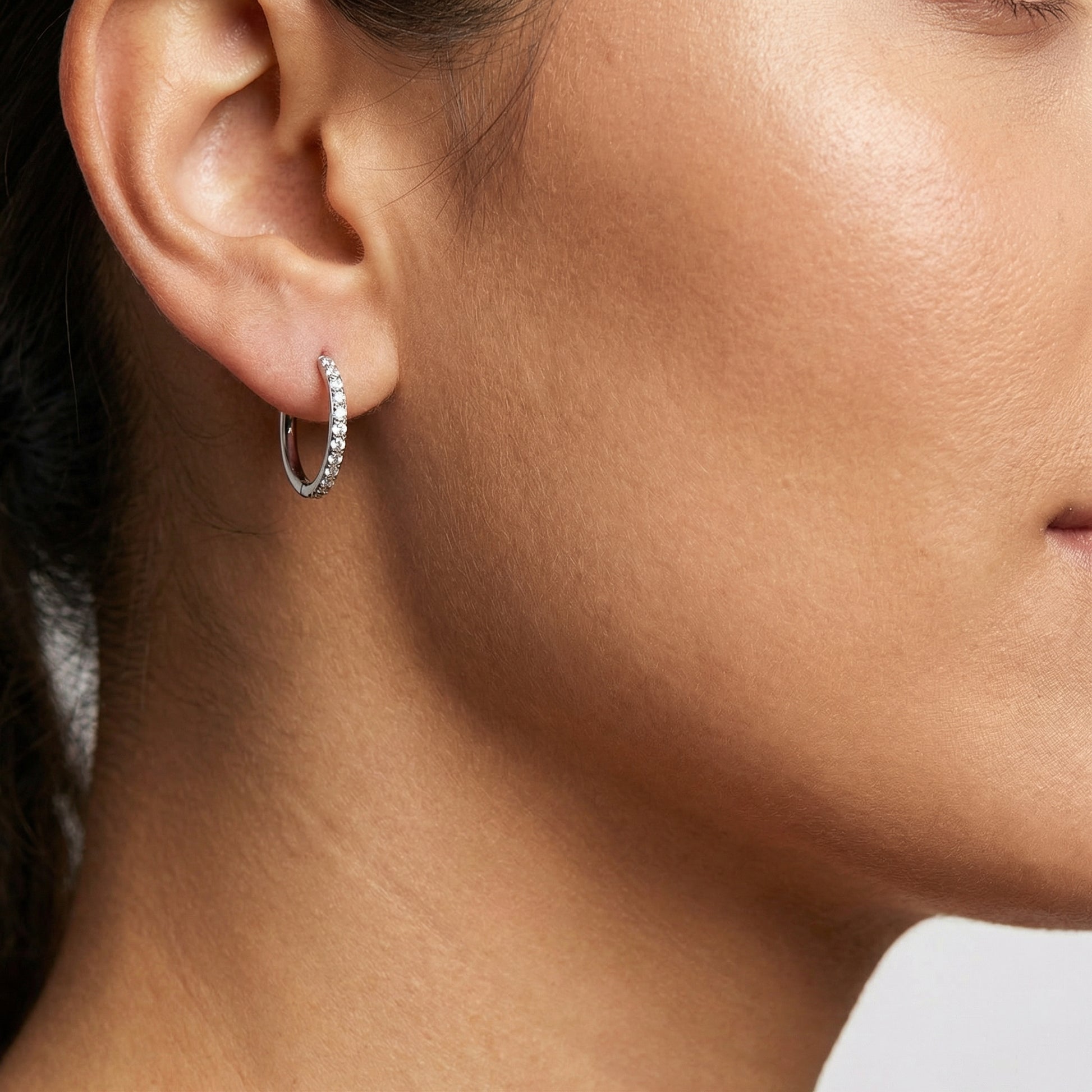 Model profile wearing a silver zircon clicker hoop in a standard placement.