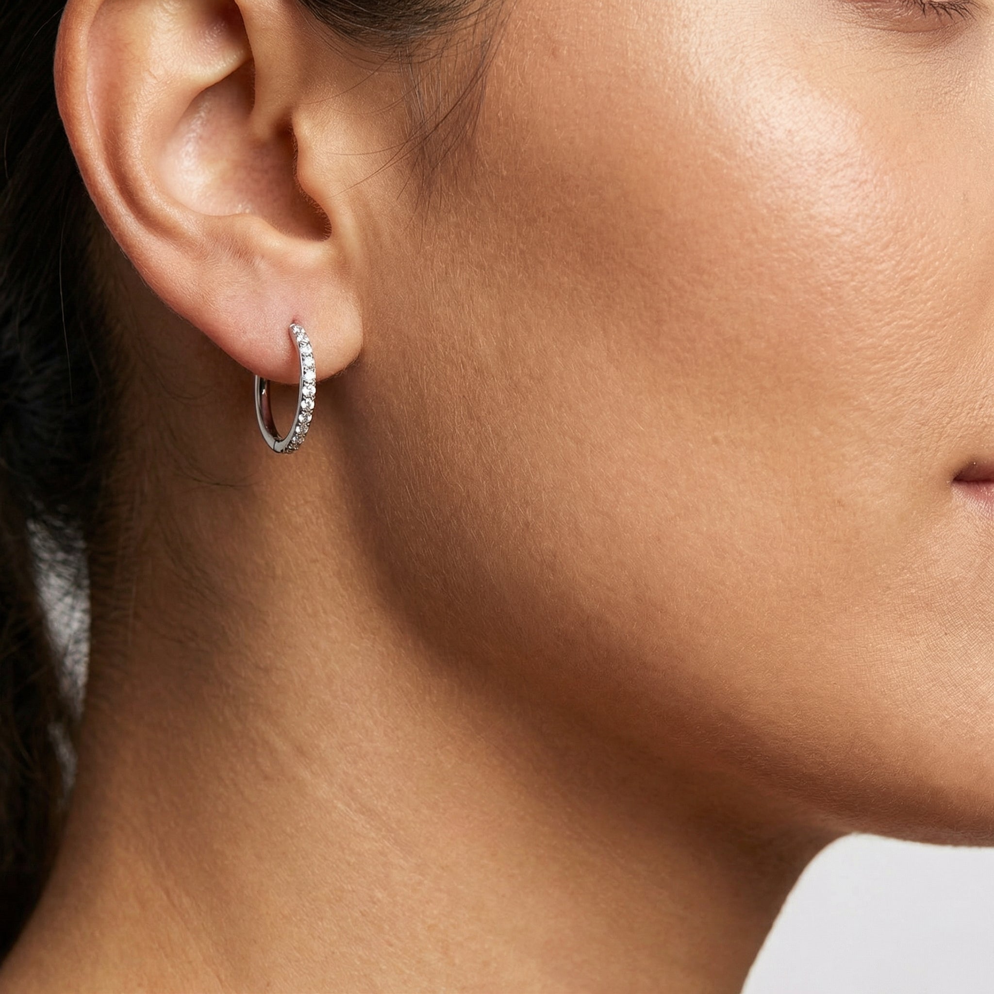 Model profile wearing a silver zircon clicker hoop in a standard placement.