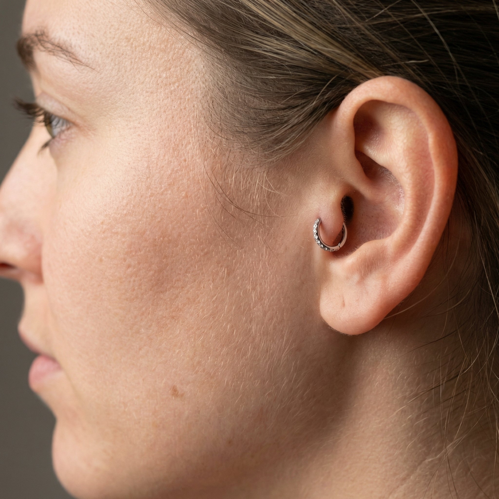 Model displaying a silver zircon clicker worn seamlessly in an inner piercing.