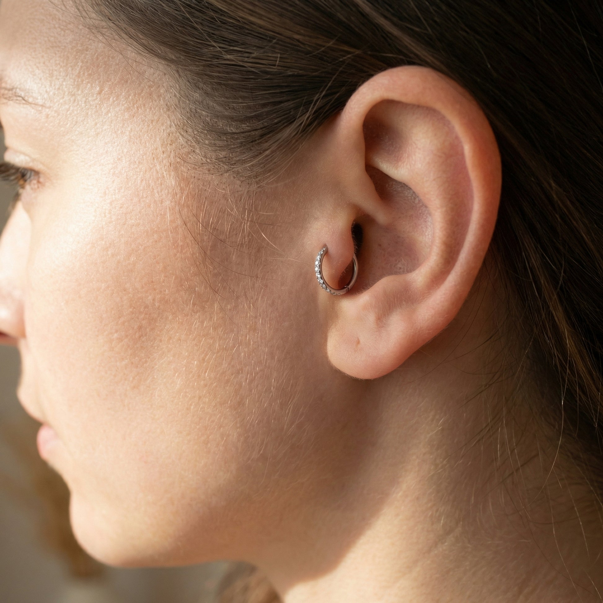 Close-up of a model wearing a silver zircon clicker in an cartilage