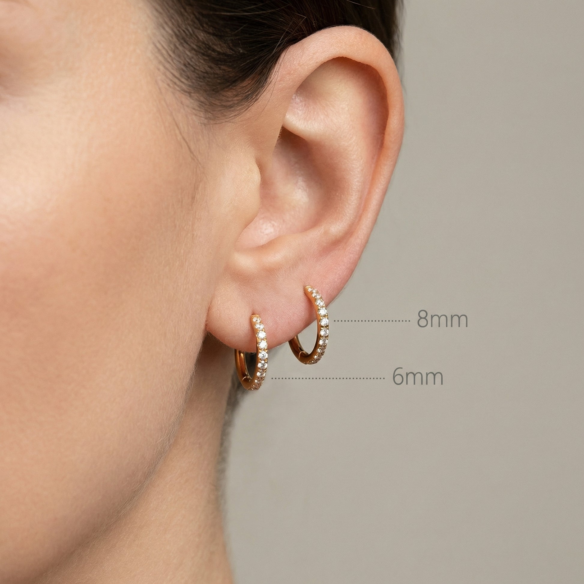 Size comparison graphic on an ear showing 6mm and 8mm gold zircon